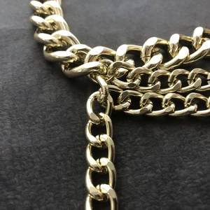 Detailed macro view of layered gold alloy curb chains with polished metallic finish