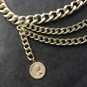 Detail of layered gold waist chain with vintage coin pendant and embossed queen portrait