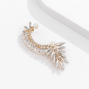 Detailed close-up of crystal wing ear cuff with pearls on a minimalist white stand