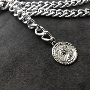 Detail of silver Cuban chain featuring a vintage coin pendant with classic relief design