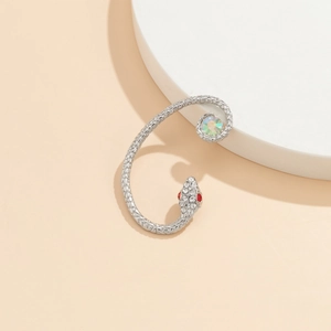 Macro shot of silver snake ear cuff with white rhinestones and a large iridescent stone