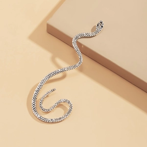 Macro detail of silver snake ear cuff featuring shimmering rhinestones on beige backdrop
