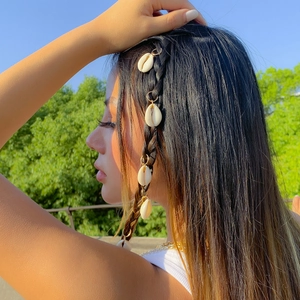 Detail of bohemian cowrie shell hair rings with gold loops on braided hair
