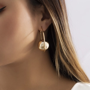 Detail van een gepolijste goudkleurige geometrische ring en bolvormige hanger bij model