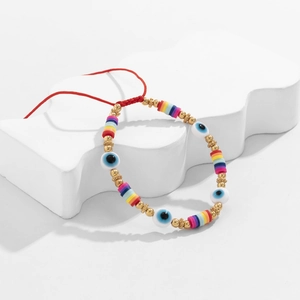 Détail d'un bracelet bohème avec perles œil grec et disques d'argile colorés sur cordon rouge