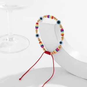 Détail du bracelet bohème avec perles mauvais œil, disques d'argile et cordon rouge