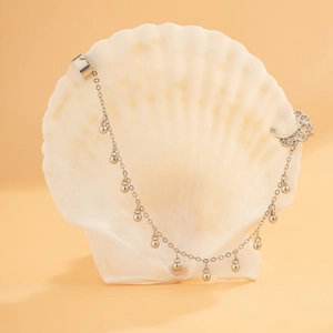 Detail der silberfarbenen Ohrmuschel-Clip-Kette mit Perlen auf einer Muschel