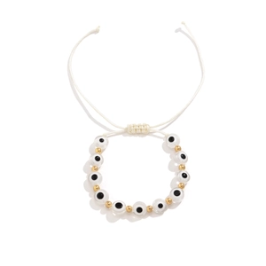 Détail du bracelet de perles mauvais œil avec accents dorés et cordon tressé blanc