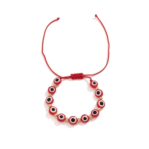 Détail du bracelet en cordon rouge tressé avec perles mauvais œil et doré chic