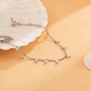 Detail of silver chain jewelry with white pearls and vintage hollow pendant on shell