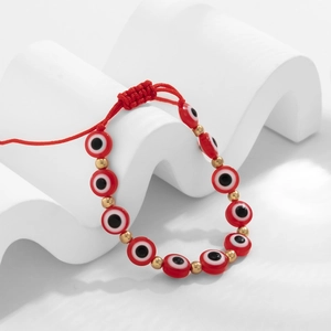 Gros plan sur les perles œil grec rouges et les entretoises dorées du bracelet réglable
