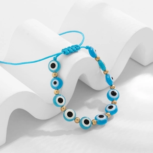 Détail du bracelet œil protecteur bleu tressé main sur support géométrique blanc