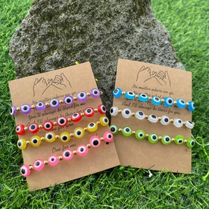 Détail de bracelets de perles mauvais œil colorés sur cartes cadeaux sur fond d'herbe