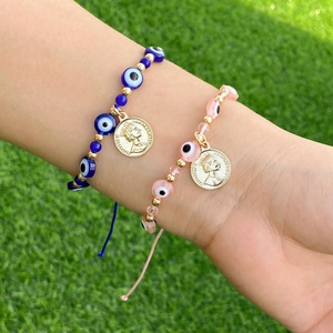 Détail de bracelets bohèmes en perles œil grec avec breloques dorées et cordons réglables