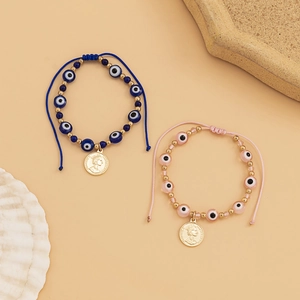 Détail de bracelets bohèmes œil protecteur avec breloques pièces Elizabeth II dorées