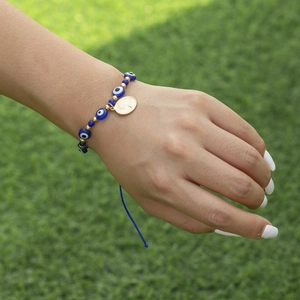 Vue détaillée du bracelet Œil de protection avec médaille dorée sur cordon tressé bleu