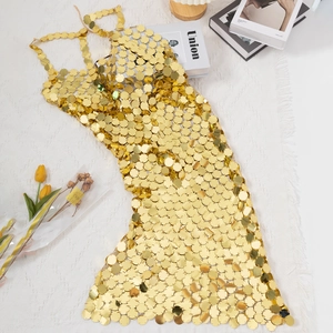 Detailed view of handmade gold sequin mini dress laid flat on a white woven rug