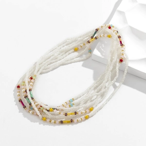 Detail einer mehrlagigen Boho-Taillenkette mit bunten Kristallperlen auf weißem Sockel