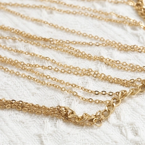 Close-up of golden multi-layer O-chain body jewelry with chunky linkage on white fabric