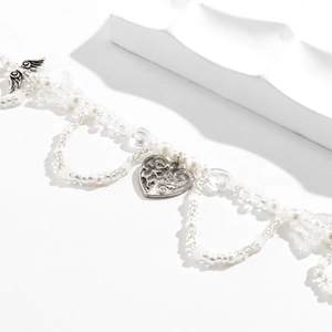 Detalle de los colgantes de mariposa y corazón en collar de perlas blancas y cristal