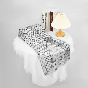 Close-up van moderne zilveren pailletten tafelloper op wit tafelkleed met woonaccessoires