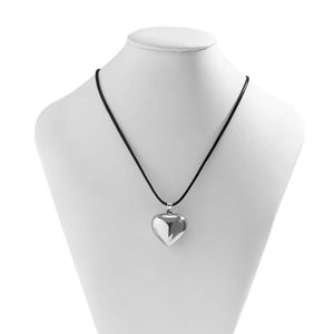Macro view of polished silver heart pendant with black wax cord on a white bust stand