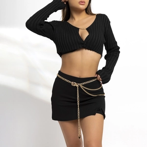 Detail of layered gold metal waist chain with heart pendants on black knit skirt