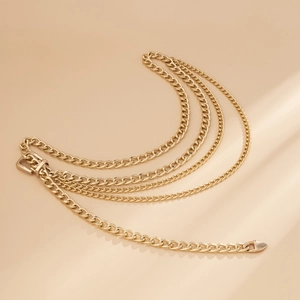 Close-up of golden multi-layer curb chain body jewelry with polished belt buckle clasp