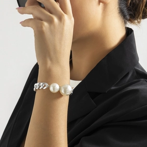Detailaufnahme eines Armbands mit großen weißen Perlen und silberner Panzerkette am Model