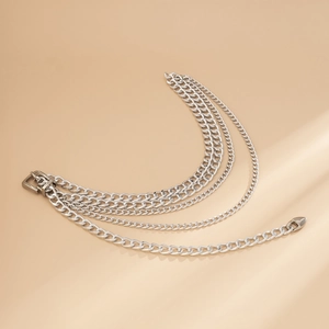 Detail view of silver multi-layer chain belt featuring thick links and a heart pendant