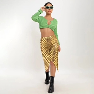 Detail view of a gold round sequin mini skirt paired with a green chain-neck top