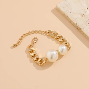 Details eines klobigen Goldkettenarmbands mit zwei großen Perlen und Karabinerverschluss