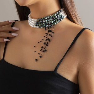 Detail of layered white pearl choker with black beaded tassels on a model neckline