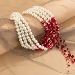 Detailed view of multilayer pearl choker with red bead tassels and beaded texture