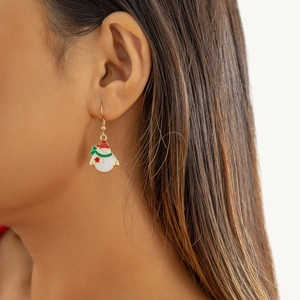 Gros plan d'une boucle d'oreille bonhomme de neige en émail avec bonnet rouge sur modèle