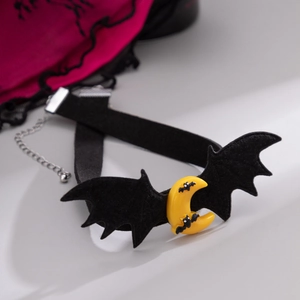 Dettaglio di un choker gotico con ali di pipistrello nere e un ciondolo a mezzaluna gialla