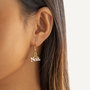 Gros plan sur les boucles d'oreilles Noel avec détails de houx portées par un mannequin