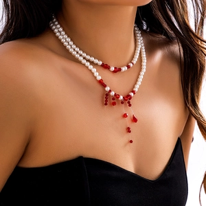 Close-up of double-layer faux pearl choker with red bead tassels for gothic style