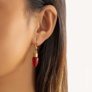 Gros plan de boucles d'oreilles ampoules rouges créatives avec des crochets en métal doré