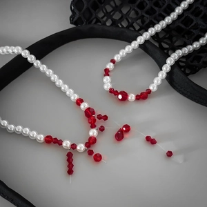 Detailed macro of gothic pearl choker with red blood drop beaded tassels on dark mesh