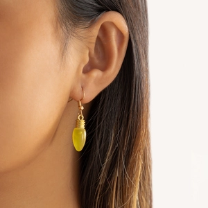 Gros plan détaillé d'une boucle d'oreille ampoule jaune portée sur un mannequin