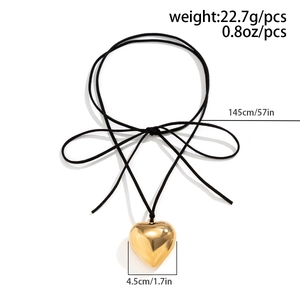 Detail of a large gold heart pendant with black wax cord and tied bow decoration