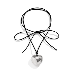 Detail of a shiny silver heart pendant on a black adjustable cord necklace with bow