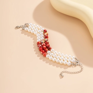 Detailed macro of a triple-layer beaded choker with white pearls and marbled red beads