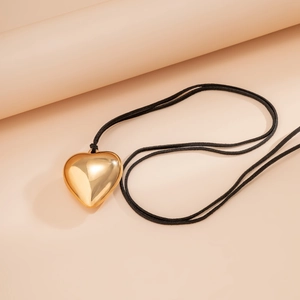 Detailed view of polished golden heart pendant with minimalist black cord necklace