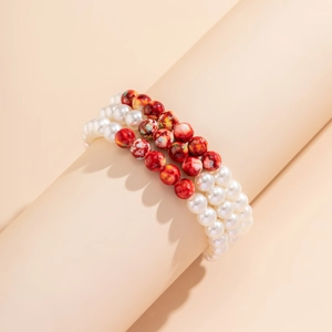 Detailed view of triple-layered elastic bracelets with red and white resin beads