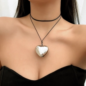 Detail shot of a large polished silver heart pendant on a black adjustable wax cord necklace