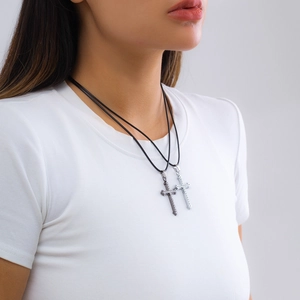 Detailansicht einer silbernen und metallschwarzen Kreuzkette mit Strasssteinen am Model