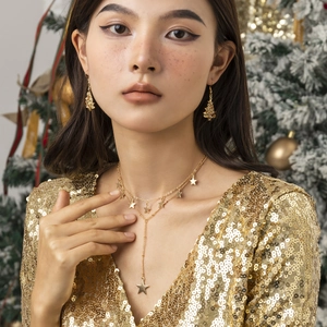 Detailopname van gouden sterrenketting en kerstboom oorbellen bij een model