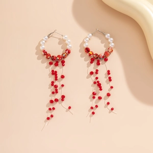 Close-up of Bohemian hoop earrings with white pearls and red beaded long tassels